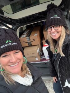 Women standing in front of a car trunk with items that will be donated.